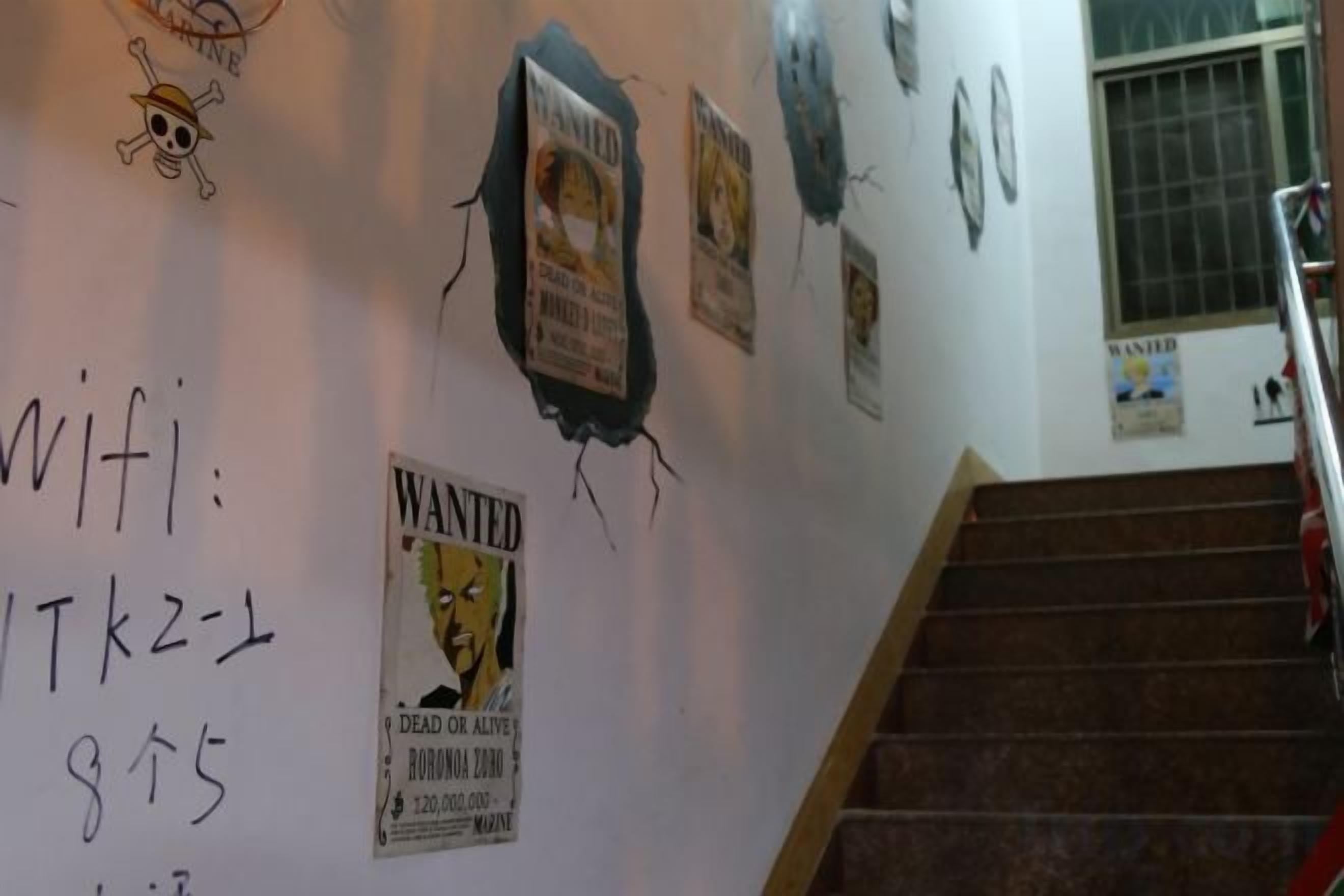 Eine Treppe mit einem handgeschriebenen Zettel an der Wand, einem Poster und einem Fenster mit Gitterstäben.