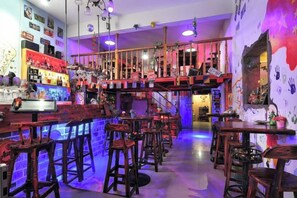 Una zona de bar con taburetes, una barra y una escalera que sube a un nivel superior.