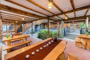 A wooden interior with a long table, benches, and a staircase leading to an outdoor area.
