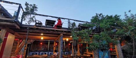 Un restaurant doté d’une terrasse, d’un patio couvert et où une personne porte des vêtements rouges.