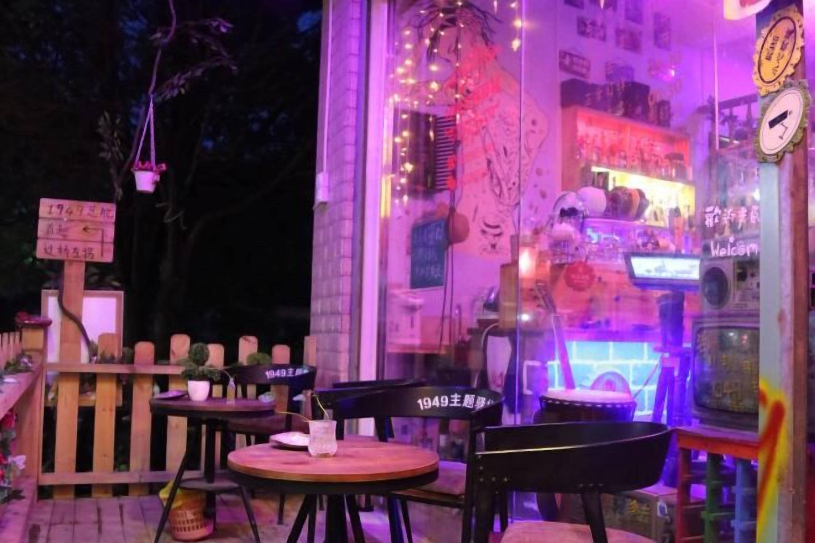 An outdoor seating area with tables and chairs, a decorative wall with lights, and a vending machine.