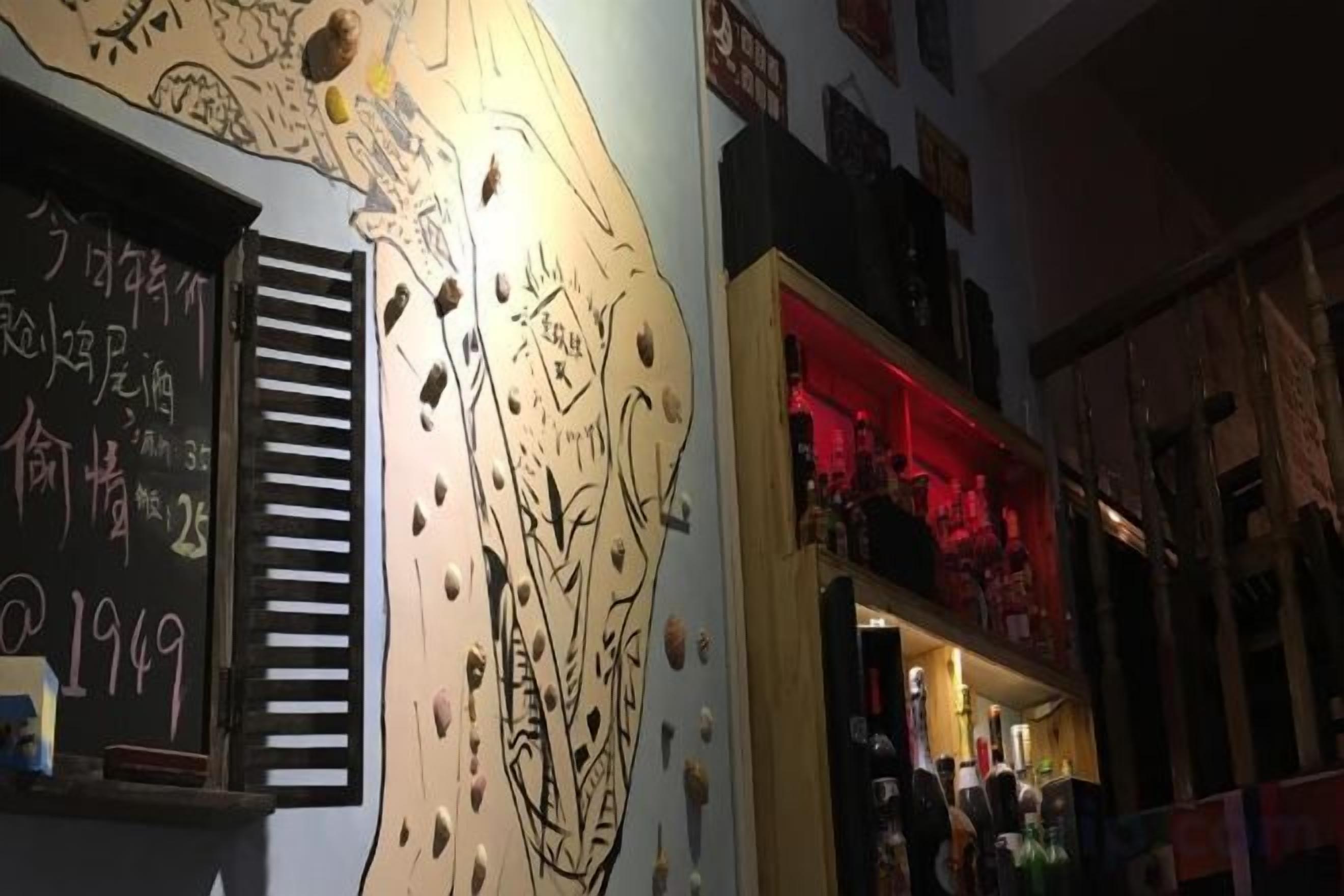 Un interior de restaurante con un menú en una pizarra, una pared con agarres para escalada y una zona de bar.