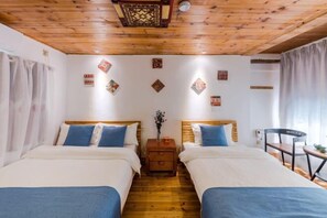 A room with two beds, wooden flooring, a ceiling fan, and decorative wall art.