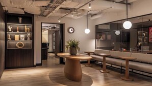 A modern interior with wooden flooring, round tables, a sofa, and a plant centerpiece. - Urban Rest - Dublin Port (Dublin)