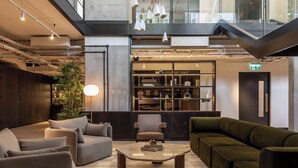 A modern lobby with a checkered floor, a central coffee table, sofas, and a bookshelf. - Urban Rest - Dublin Port (Dublin)