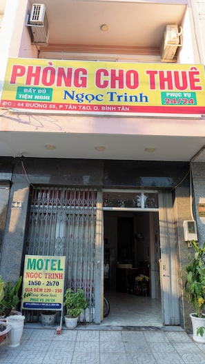 Un edificio con un letrero destacado del motel 'Ngoc Trinh', que incluye el horario de atención y el rango de precios.