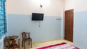 A room with a television mounted on the wall, a wooden chair, a small round table, and a door. - Ngoc Trinh Hotel Binh Tan by Zuzu (Ho Chi Minh Municipality)