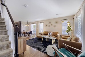 A spacious living area with a staircase, a dining table, and a sofa set.