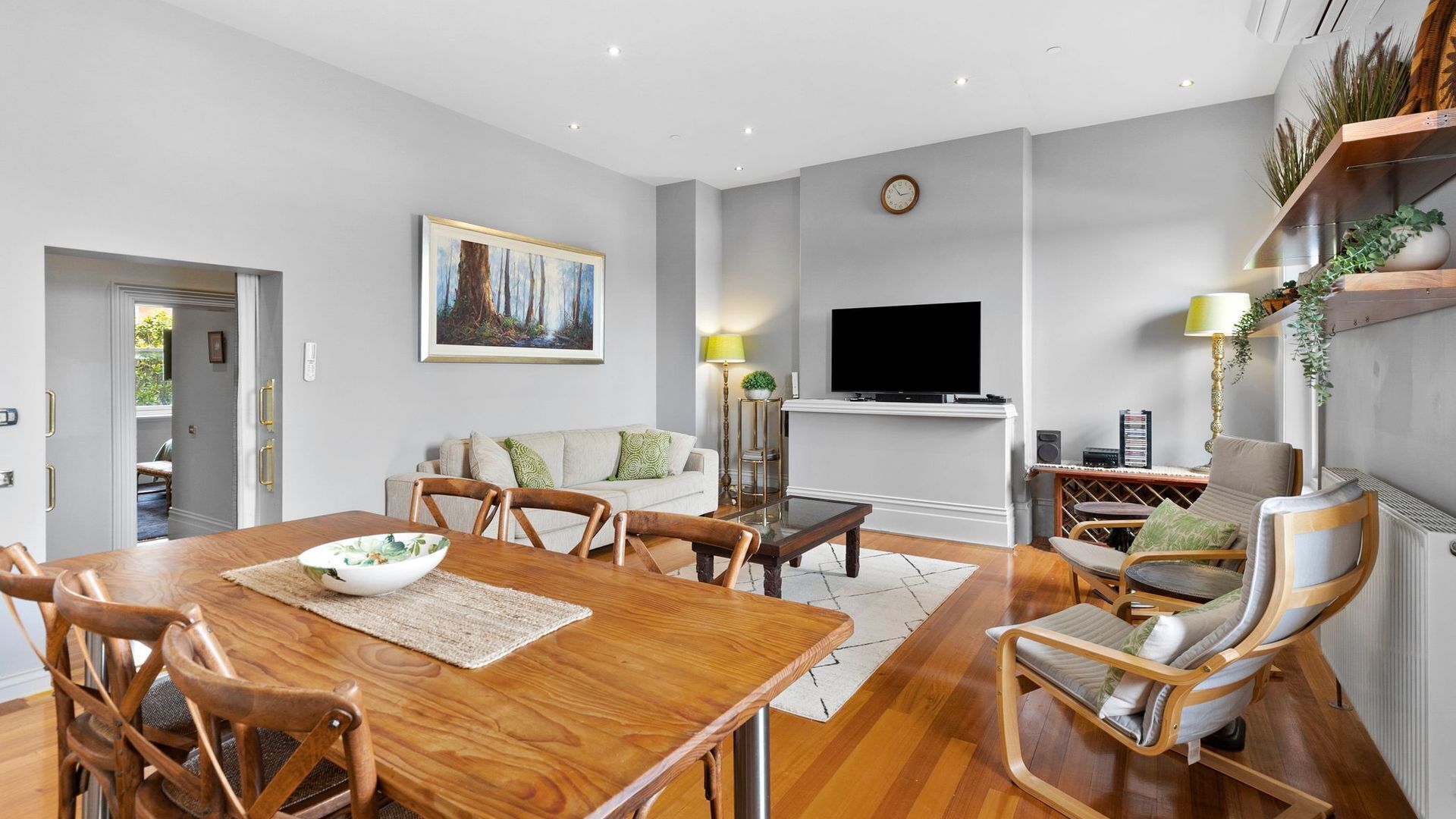 A modern living room with a wooden dining table, chairs, a sofa, a TV, and a fireplace.