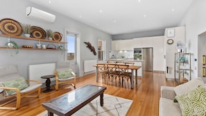 A spacious living area with a dining table, chairs, a sofa, and a coffee table. - Pelicans at the Ozone (Queenscliff)