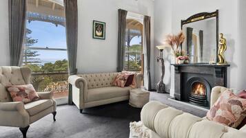 A living room with a fireplace, a sofa, armchairs, and a view of the outdoors.