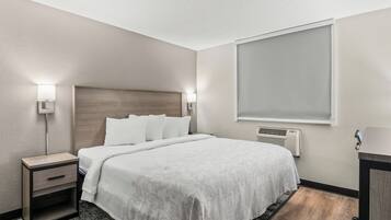 A hotel room with a bed, bedside tables, a window, and a wall-mounted air conditioner.