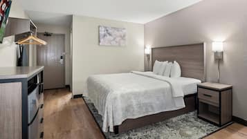 A hotel room with a bed, bedside tables, a desk, and a wardrobe.