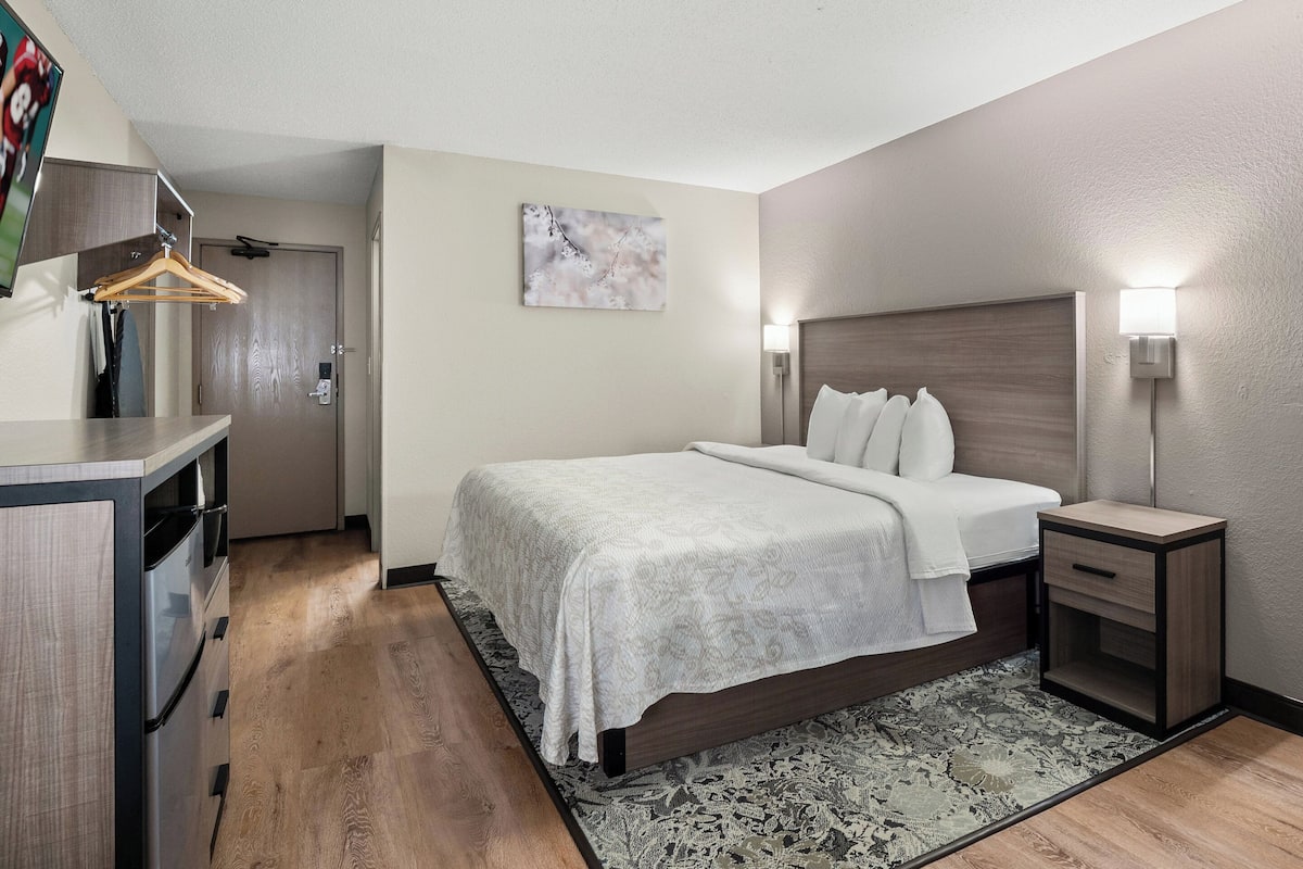 A hotel room with a bed, bedside tables, a desk, and a wardrobe.