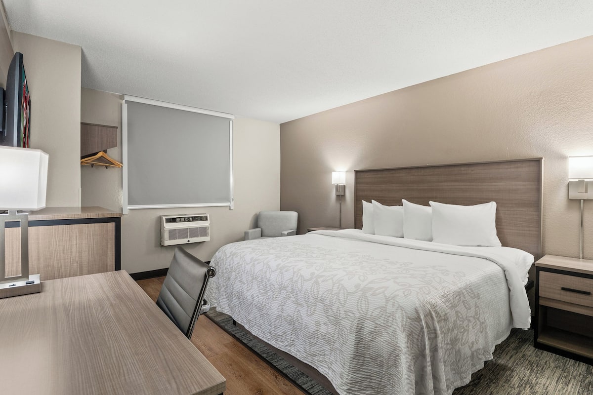 A hotel room with a large bed, bedside tables, a desk, and a wardrobe.