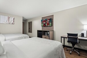 Habitación de hotel con dos camas, un escritorio con computadora, televisor y microondas.