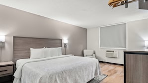 Una habitación de hotel moderna con una cama grande, mesitas de noche, un escritorio y una silla.