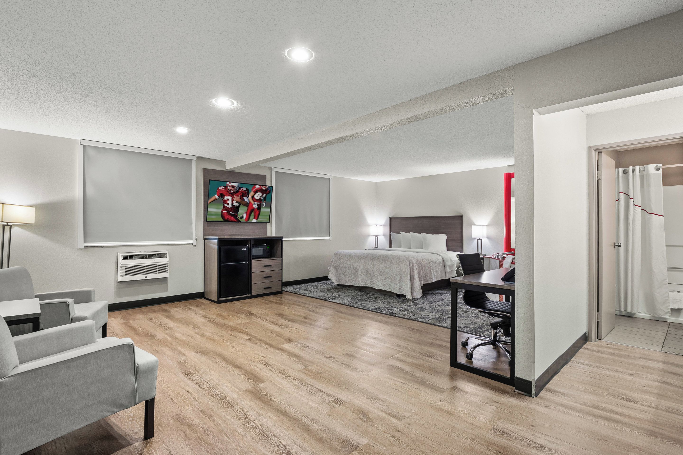 A modern hotel room with a bed, desk, and seating area.