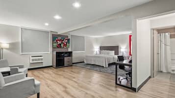 A modern hotel room with a bed, desk, and seating area.