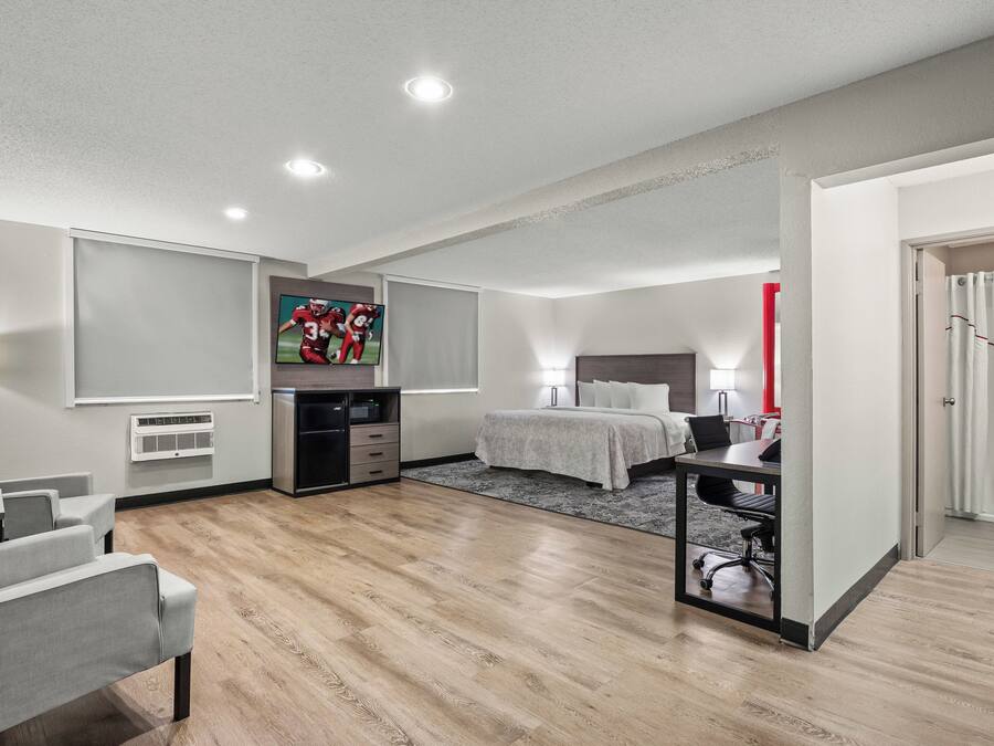 A modern hotel room with a bed, desk, and seating area.