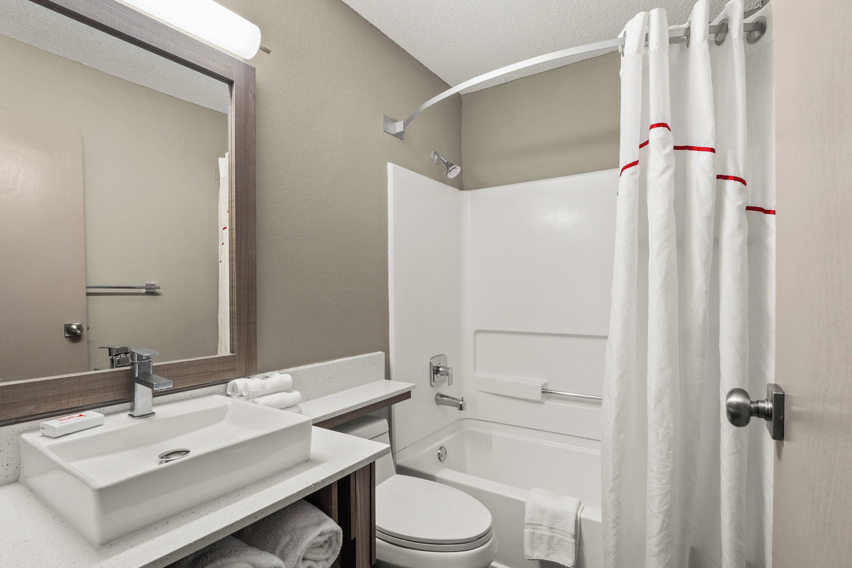 Une salle de bain moderne équipée d’un lavabo, d’un miroir, de toilettes et d’une baignoire.