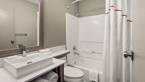 Un baño moderno con lavamanos, espejo, inodoro y bañera.