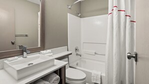 Un baño moderno con lavamanos, espejo, inodoro y bañera.