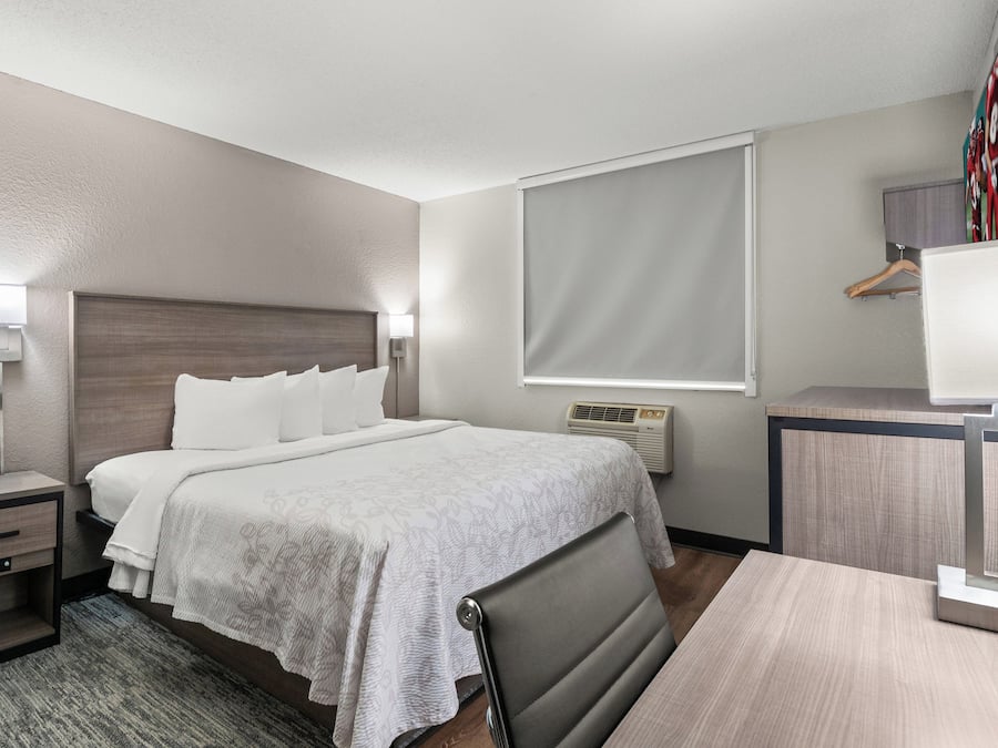 Et hotelværelse med seng, sengeborde, et skrivebord og en stol.