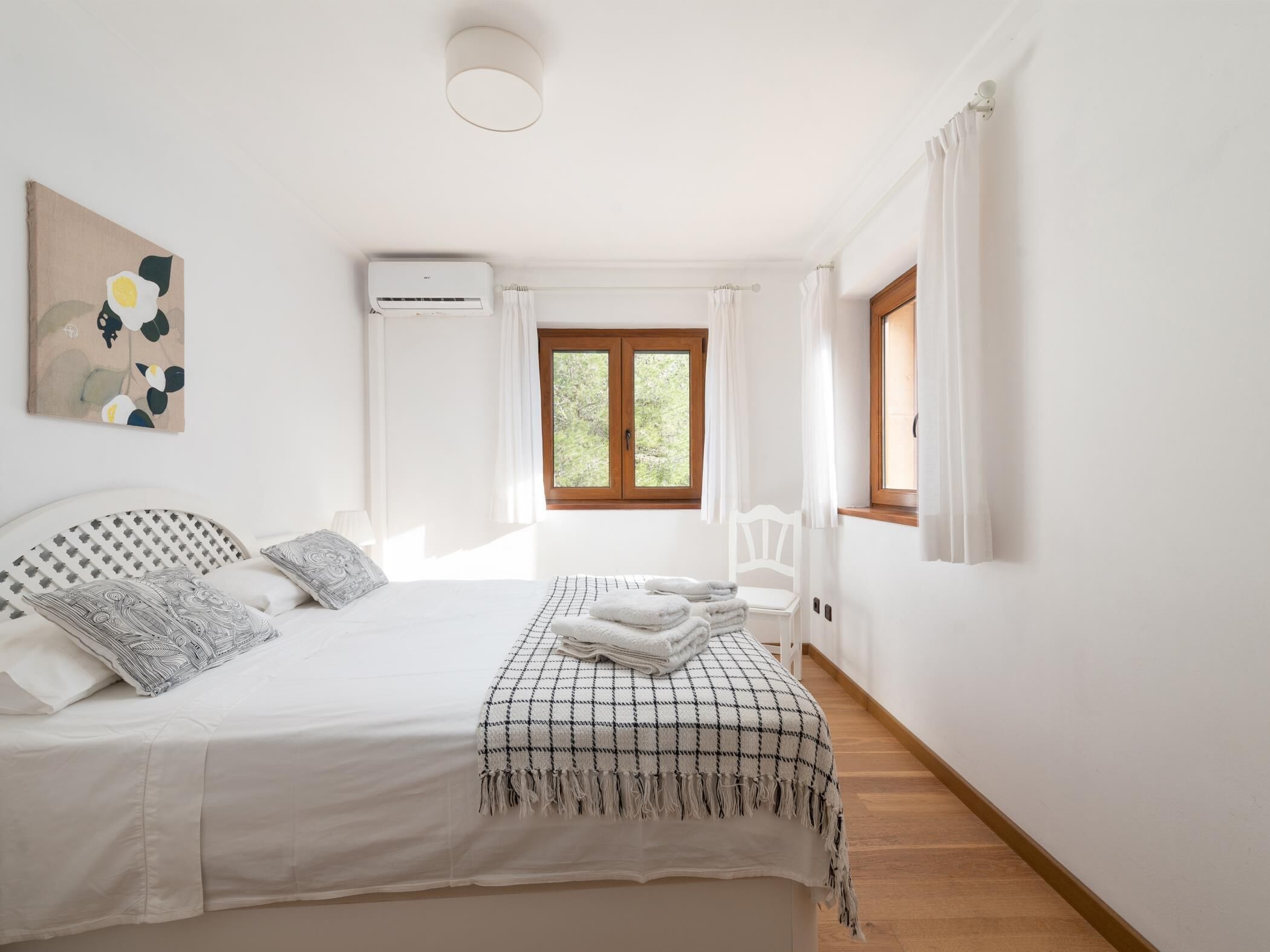 Ein Schlafzimmer mit Bett, Nachttisch, Stuhl, Fenster und Klimaanlage.