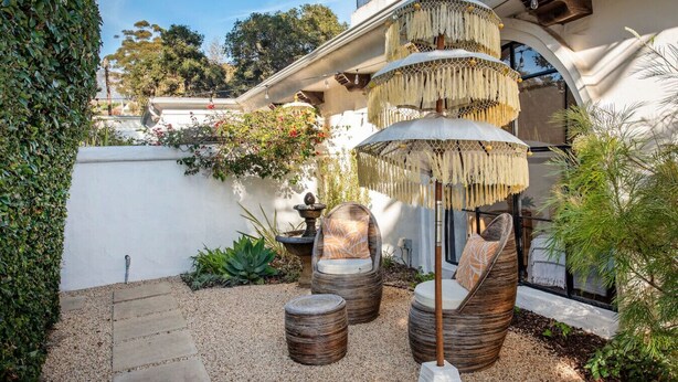 A patio with wicker furniture, a decorative umbrella, and a small fountain.