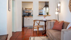 A compact living space with a kitchenette, a dining area, and a seating area with a sofa and a chair.