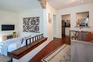 Un salon moderne avec un canapé, un banc en bois, un téléviseur et un élément décoratif mural.