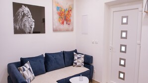Una sala de estar moderna con un sofá azul, una mesita blanca y una puerta con ventanas cuadradas.