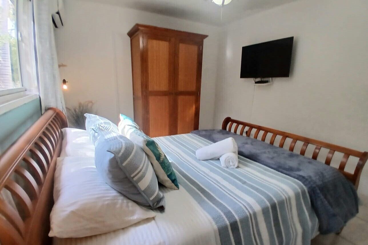 Une chambre à coucher avec un lit, une armoire en bois et un téléviseur fixé au mur.