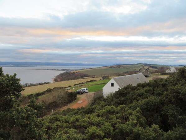 A rural landscape with a white building, a path, and a body of water in the distance.