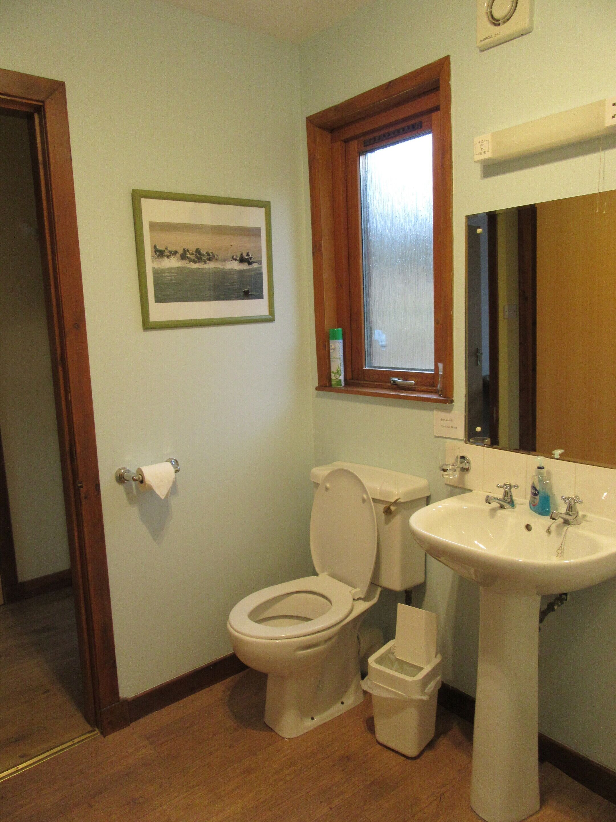 Ein Badezimmer mit Toilette, Waschbecken und einem gerahmten Bild an der Wand.