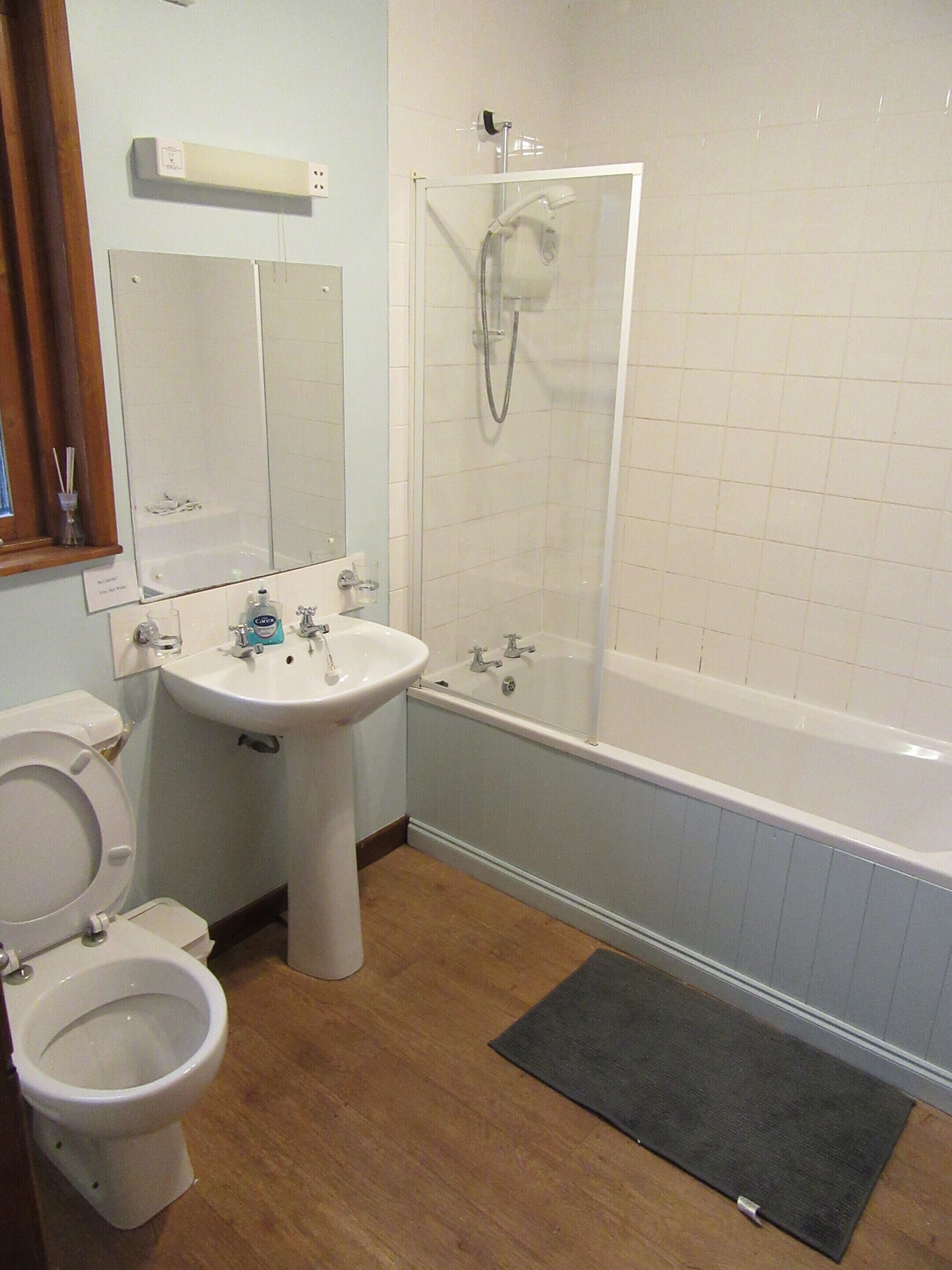 A bathroom with a toilet, sink, bathtub, and shower.