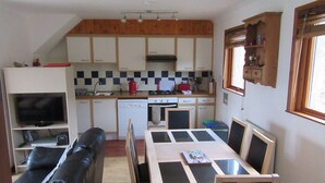 A compact kitchen with a dining area, a television, and a sofa.