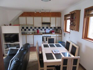 A compact kitchen with a dining area, a television, and a sofa.