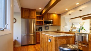 Une cuisine moderne avec des meubles en bois, des appareils en acier inoxydable et un plan de travail en granit.