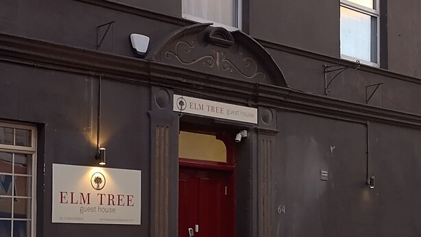 A building with a sign reading "ELM TREE guest house" and a red door. - Elm Tree Guest House (Weston-super-Mare)