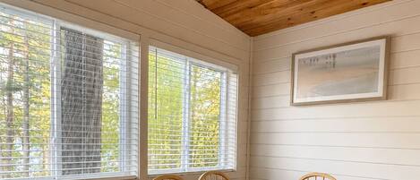 A dining room with a wooden table and chairs, a ceiling fan, and windows with blinds.