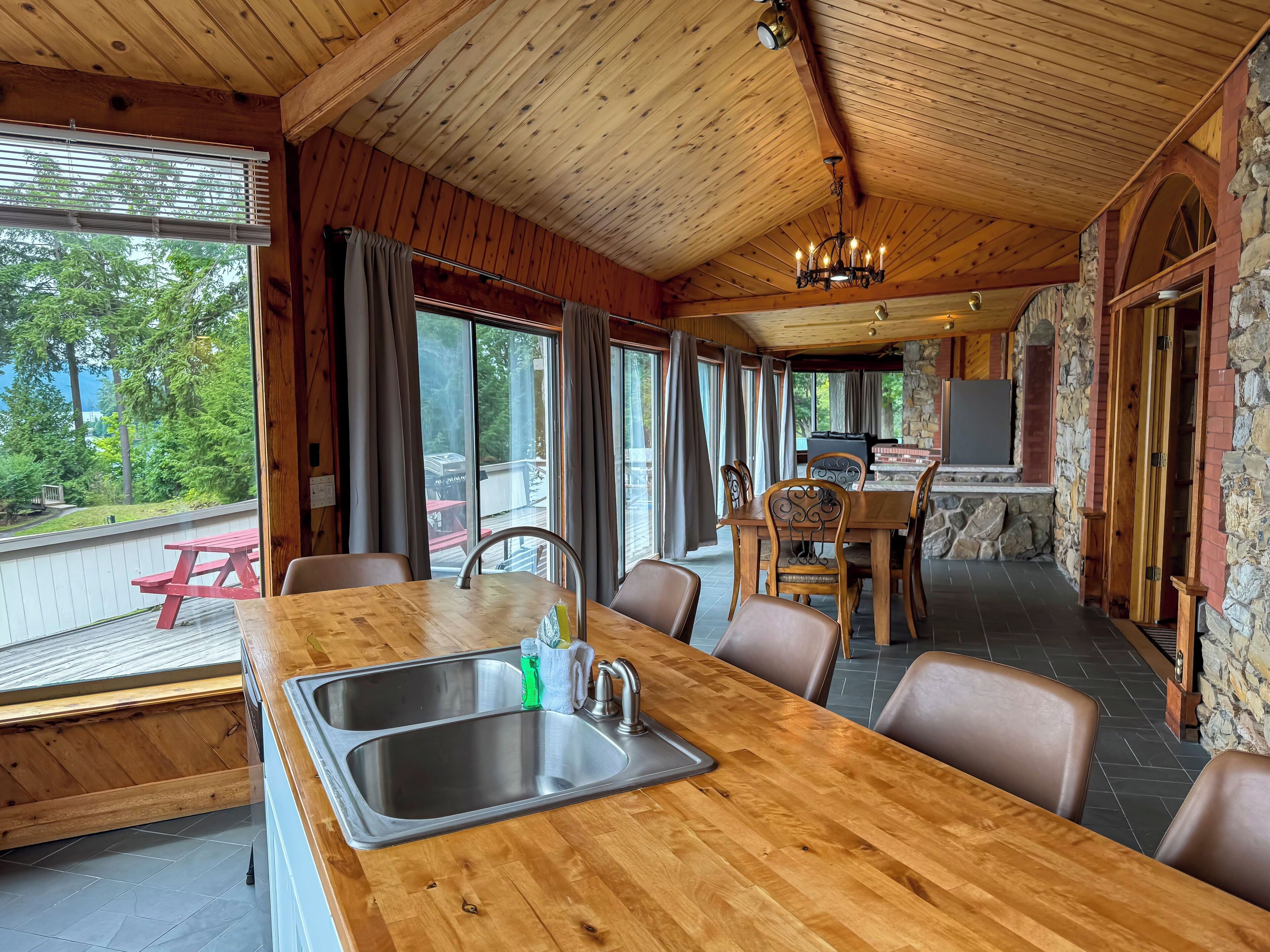 A wooden dining area with a large table, chairs, and a built-in sink.