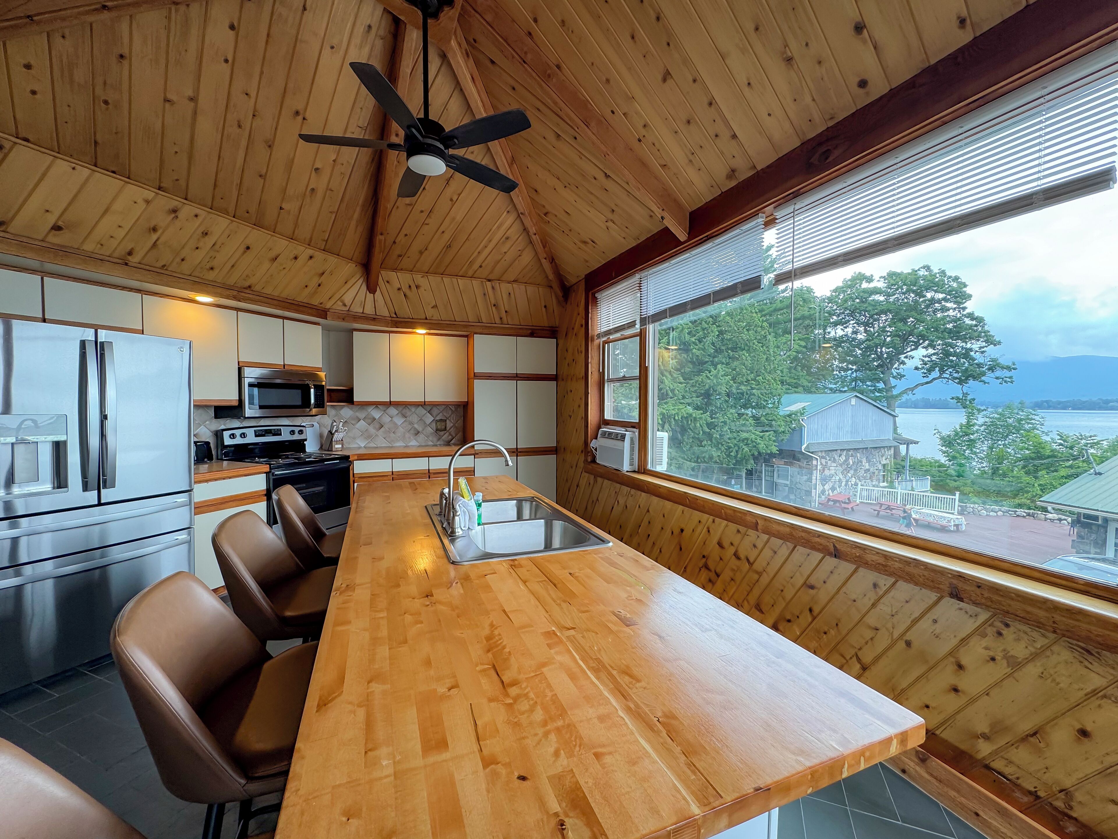 A kitchen with wooden walls, a wooden dining table, and a view of the outdoors.