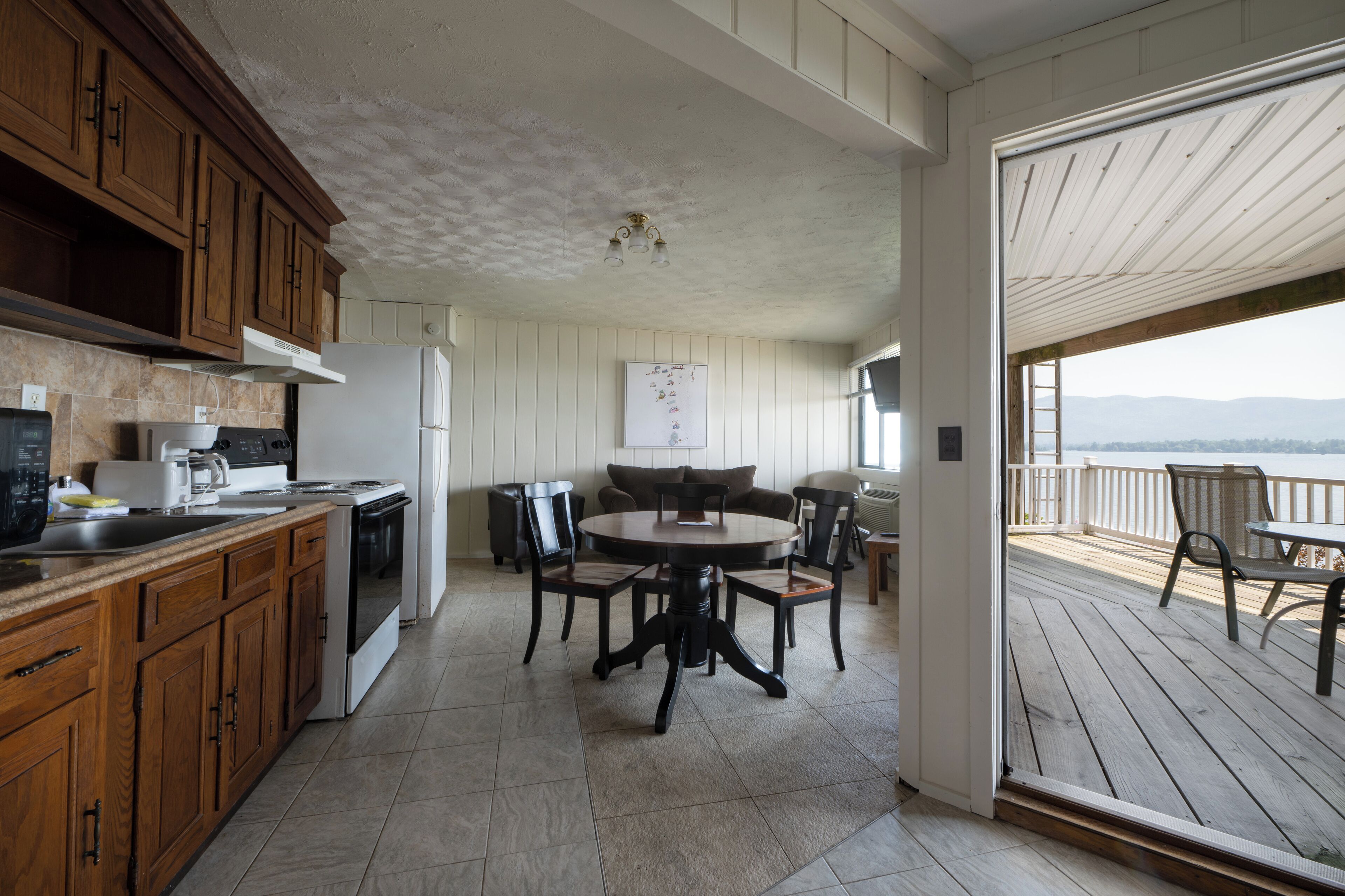 Una cocina con armarios de madera, una estufa y un refrigerador. Hay un comedor con una mesa y sillas.
