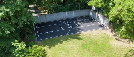 Una cancha de baloncesto al aire libre rodeada de árboles.