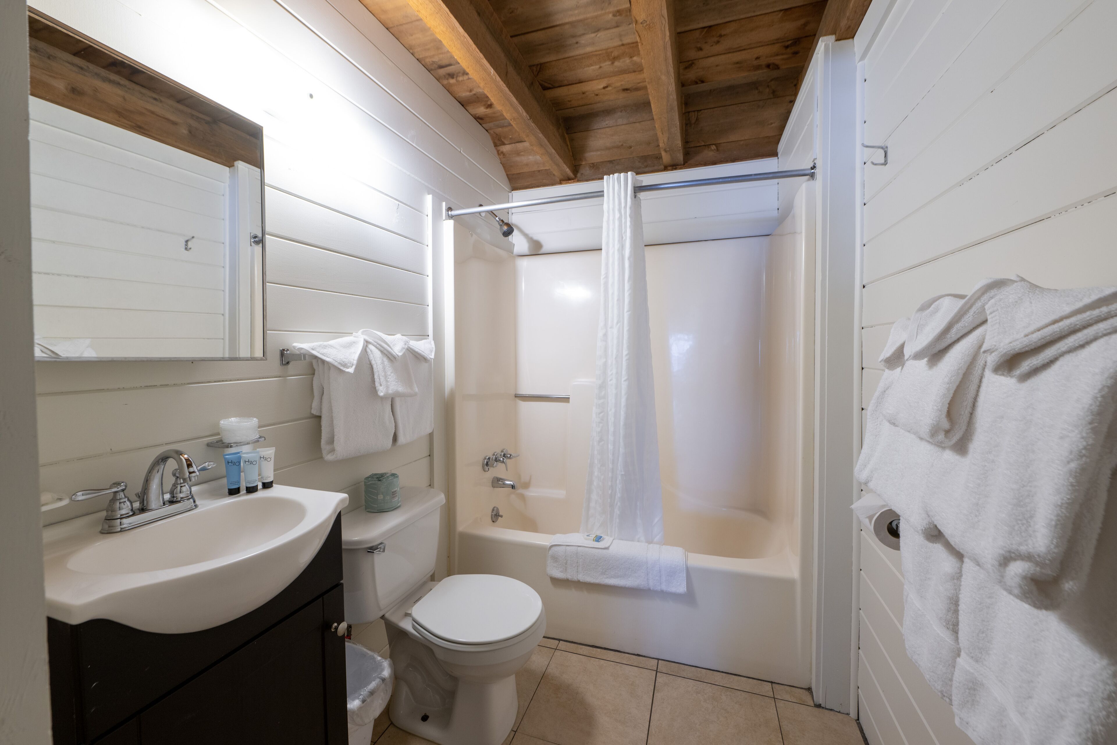 A bathroom with a sink, toilet, bathtub, and shower curtain.