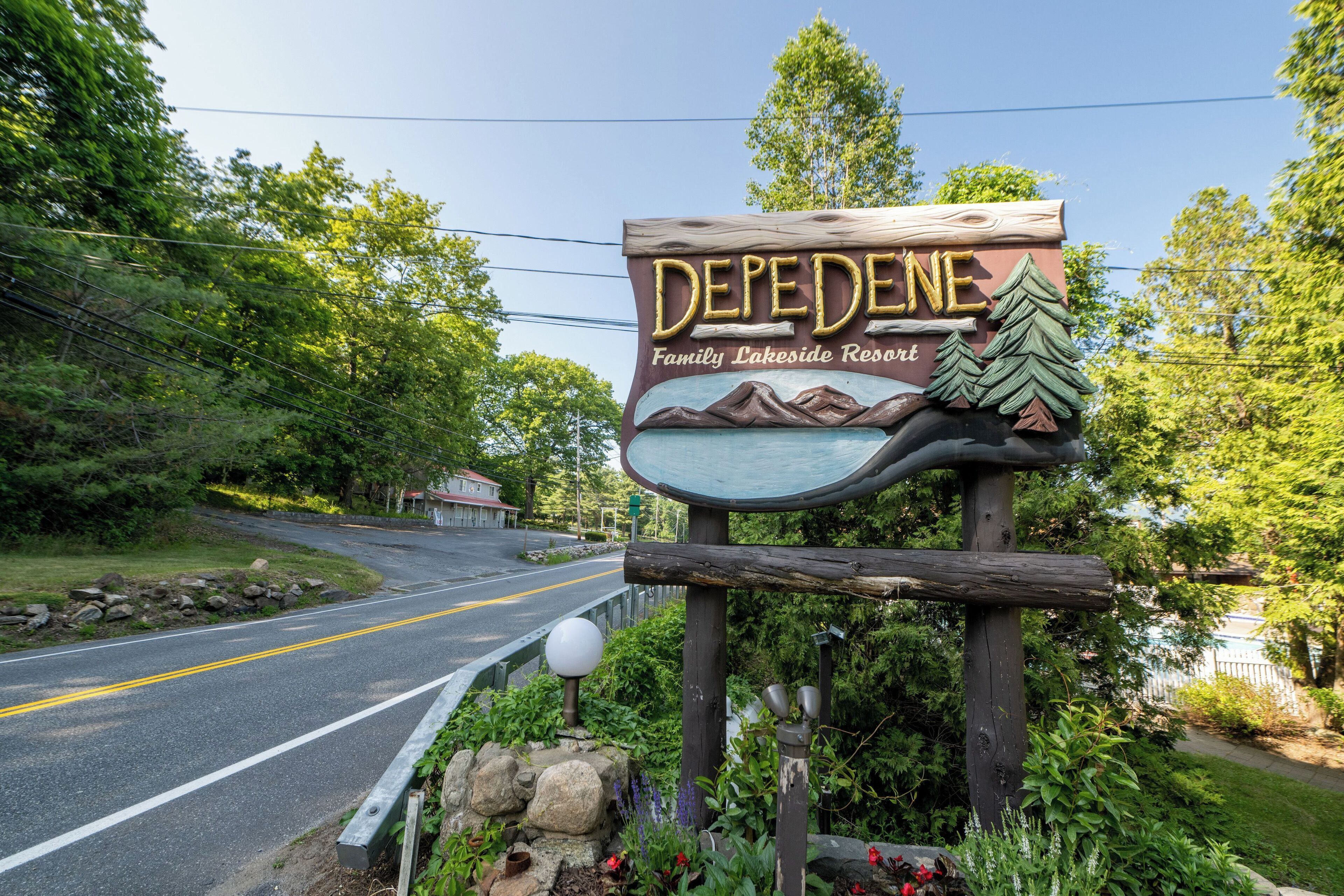 A wooden sign with the text "DEPEDENE Family Lakeside Resort" and a mountain landscape illustration.