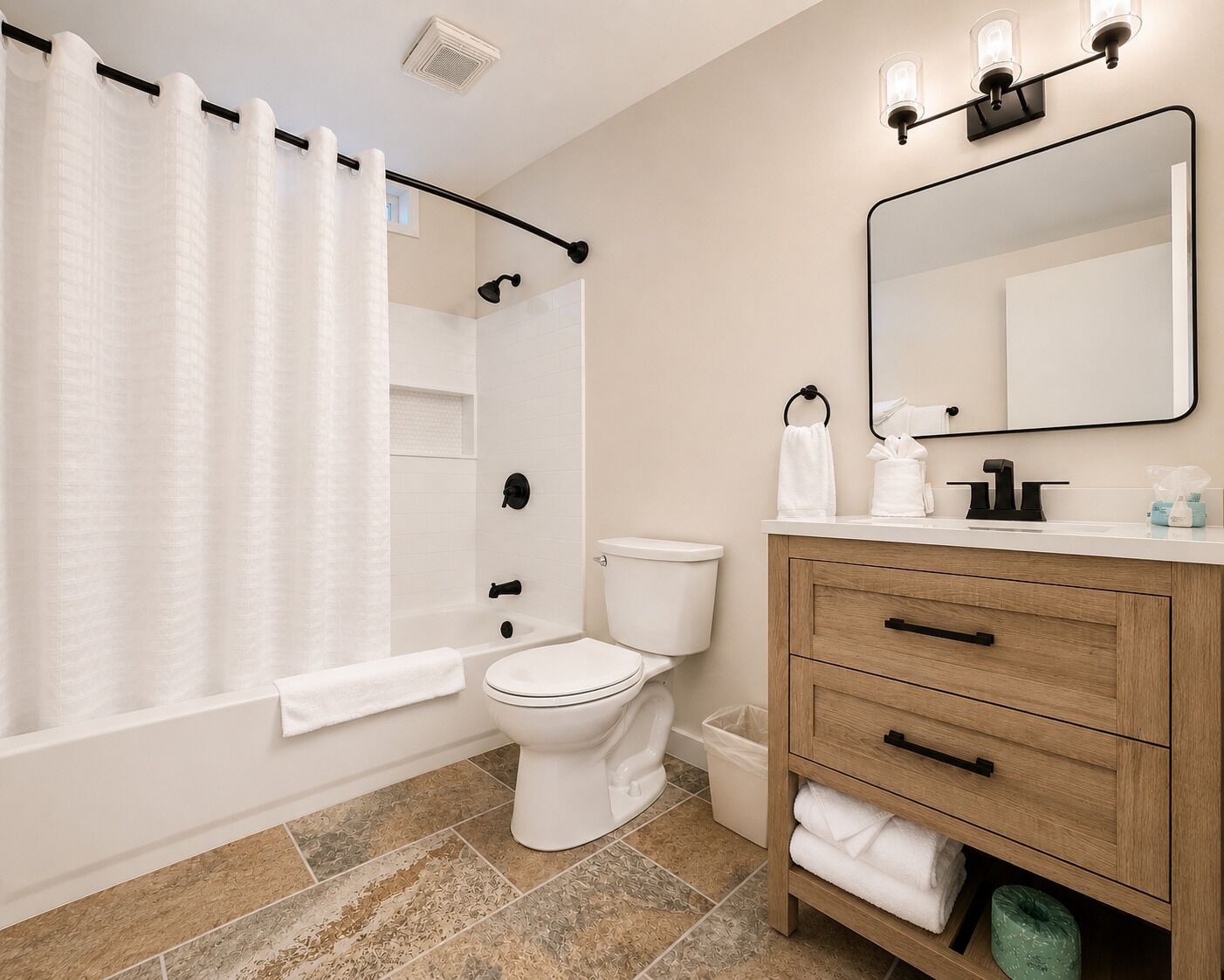 A bathroom with a shower curtain, toilet, vanity with a mirror, and a sink.