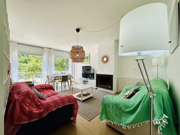 Un salon comprenant un canapé, un téléviseur, une cheminée et un coin repas avec une table et des chaises.